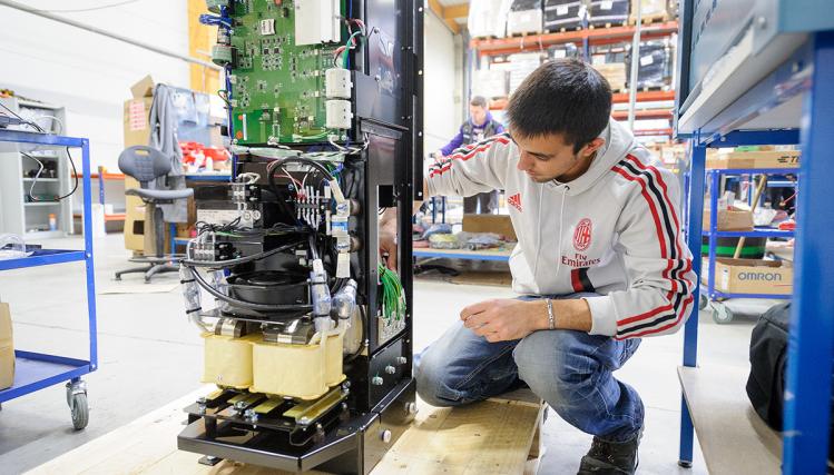 Un jeune technicien en train de travailler accroupi devant une machine
